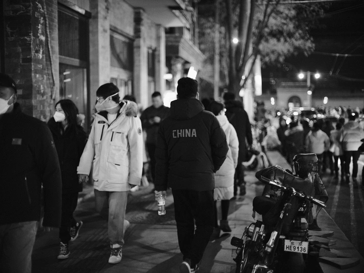 一张黑白照片 描绘了夜晚一群人走下街道的情景。