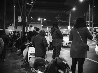 一张黑白照片 描绘了夜晚一群人走下街道的情景。