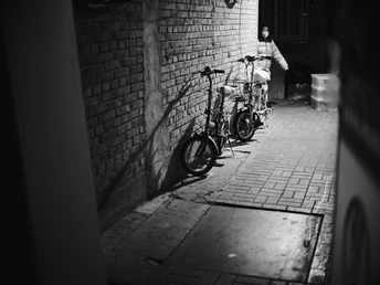 一张黑白照片 描绘了一条黑暗的巷子 一辆自行车靠在墙上。