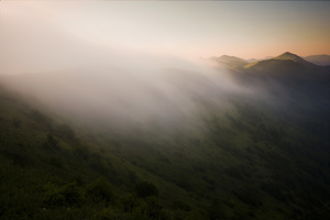 阳光穿过山间的雾气和云层 照耀在山脉中的一个山谷上。