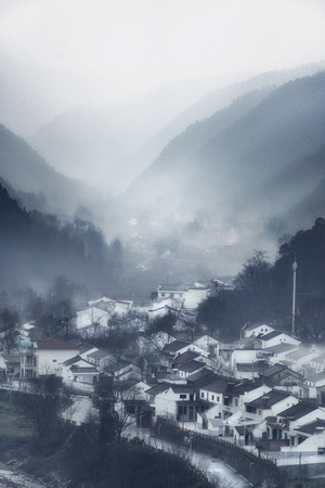 山中的一个小村庄 山丘上有雪 空气中弥漫着雾。