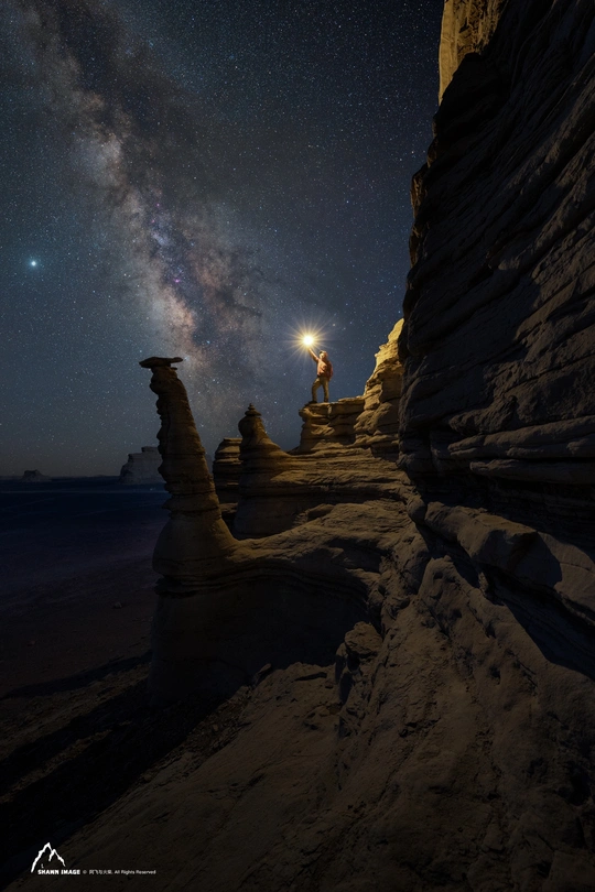 站在海滩上的男人在夜晚仰望星空