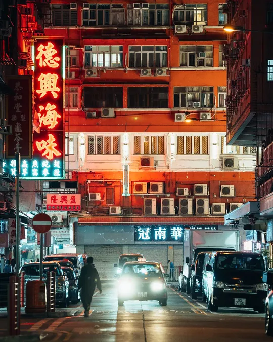 夜晚的城市街道 汽车沿着街道行驶 一名男子穿越街道。