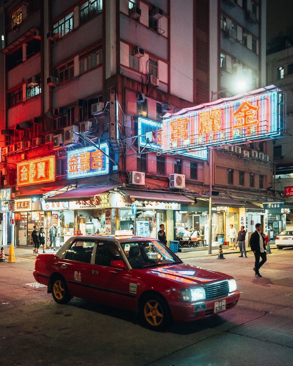 夜晚的城市街道 一辆红色汽车停在有霓虹灯标志的建筑物前
