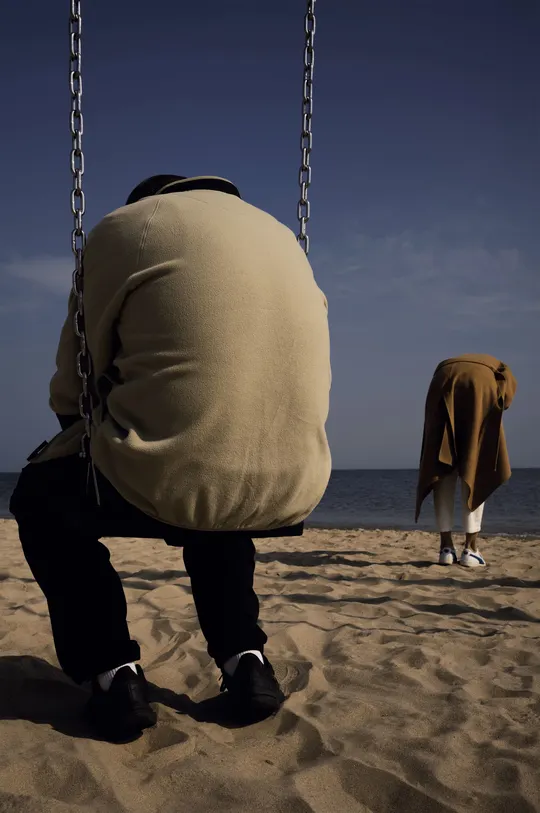 一个人坐在靠近海洋的海滩边的秋千上