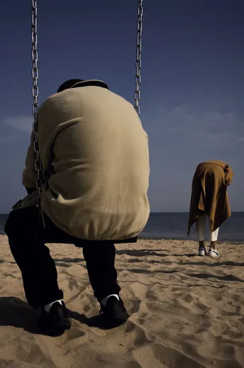 一个人坐在靠近海洋的海滩边的秋千上