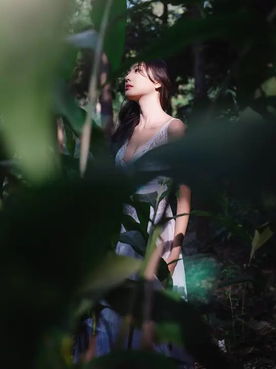 一位年轻女子穿过森林 森林中有绿色的植物和树木。