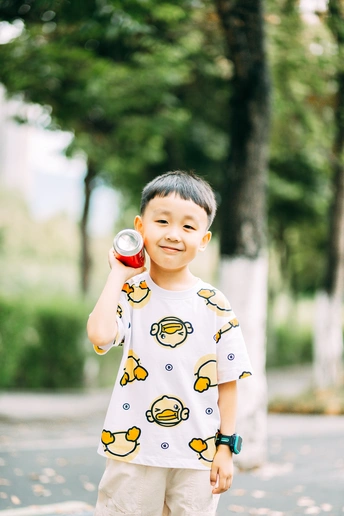 公园里 一个穿着睡衣、手里拿着罐头的小男孩站在滑板上