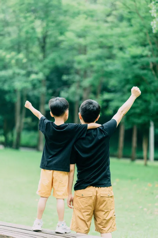 两个小男孩站在公园里 手臂举起来 双手举起来。