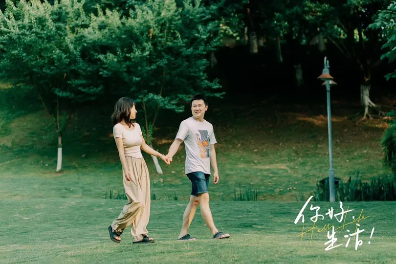 一位年轻男子和女子手牵手穿越草地