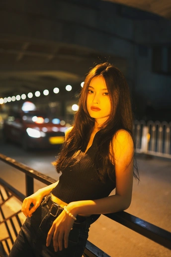 一位穿着黑色连衣裙的年轻女子在夜晚站在桥上