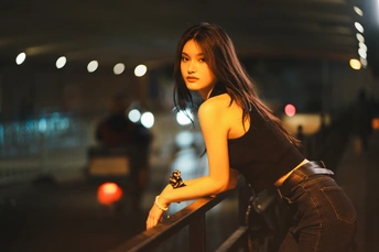 一位年轻女子在夜晚拍照 倚靠在扶手栏杆上