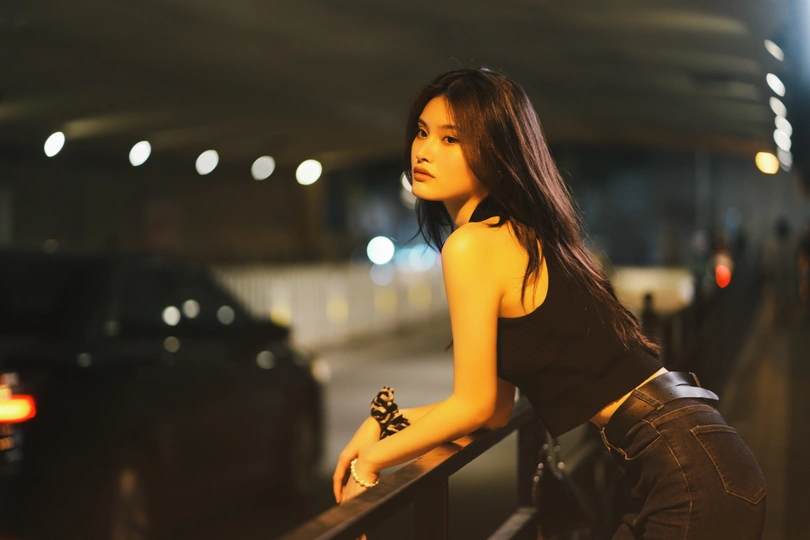 一位穿着黑色衣服的年轻女子在夜晚倚靠在栏杆上