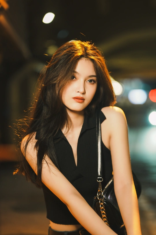 美丽年轻的黑衣女郎在街头为肖像画摆姿势