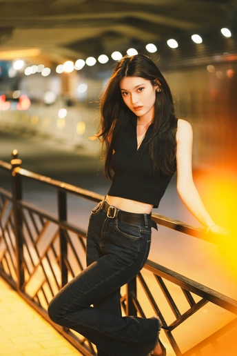 一位穿着黑色牛仔裤的美女站在铁轨旁边