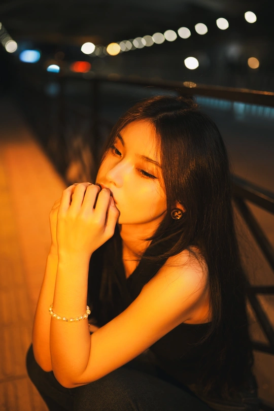 一位年轻女子晚上坐在人行道上