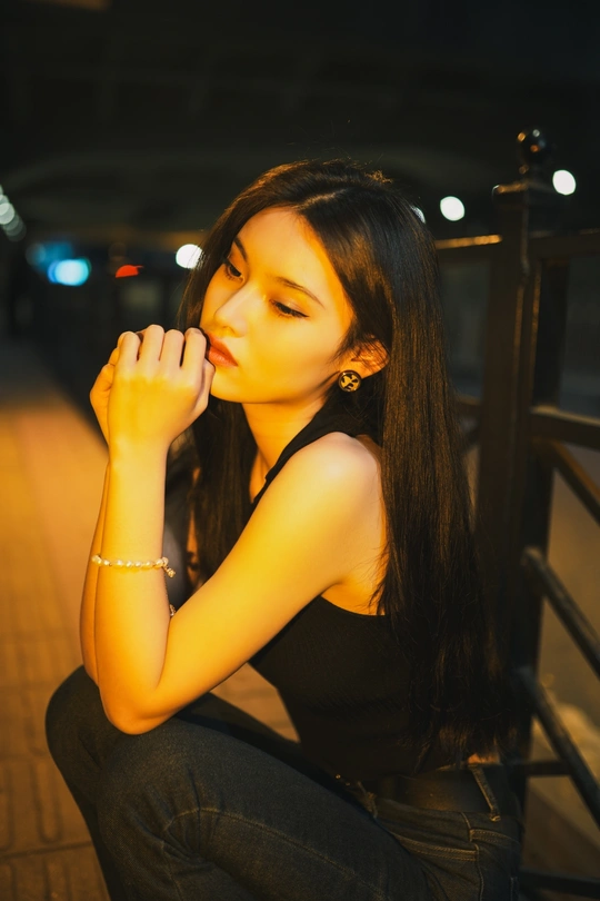 一个年轻女子晚上坐在户外 手按在胸口上。