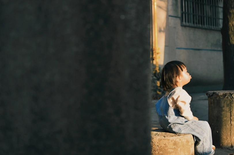 一个小女孩坐在街上看着一个男孩