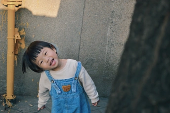 一个小女孩穿着工作服站在人行道上微笑