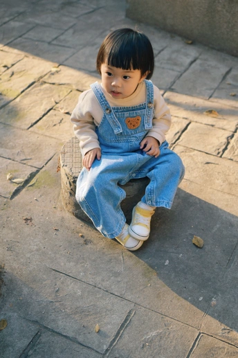 一条小裙子的小女孩坐在人行道上