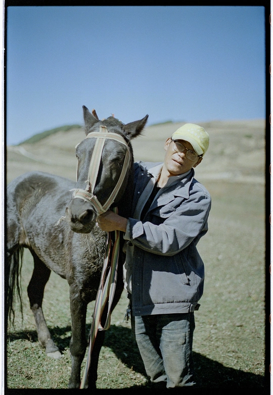 一个男人在田地里抱着一匹马。