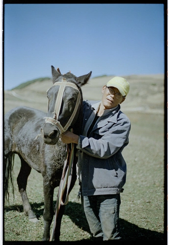 一个男人在田地里抱着一匹马。
