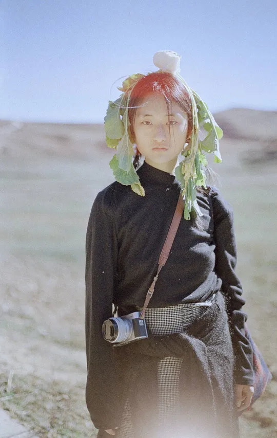 一个穿着服装的女孩戴着相机站在沙漠中。