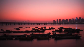 夕阳下 天空中太阳低垂 有一片有船的水域。