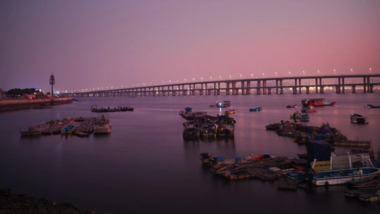 夕阳下 一座横跨在广阔水面上的长桥。