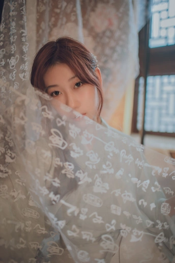 窗前一位戴着白色面纱的年轻女子