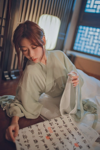 坐在桌子旁读报纸的年轻女子