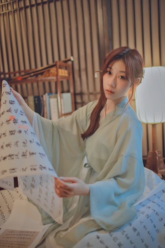 一个穿着蓝色衣服的年轻女人坐在床上 伴着乐谱