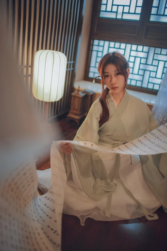 一个穿着白色连衣裙的漂亮年轻女子坐在房间的窗前