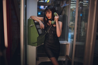 一个穿着黑色连衣裙的年轻女子拿着一部绿色手机