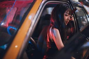 一个穿着红色连衣裙的年轻女子坐在车里