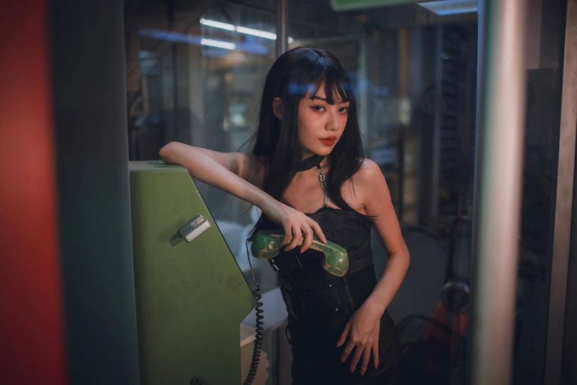 一位身穿黑色连衣裙的年轻女子拿着一个绿色瓶子摆姿势