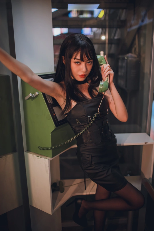 一个穿着黑色连衣裙的年轻女子拿着一部绿色手机