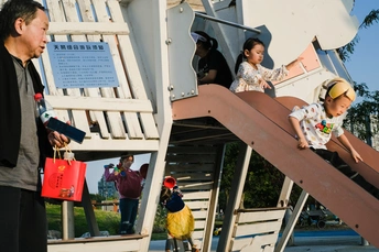 一个男子和一个小女孩在游乐场玩耍 其他人在观看