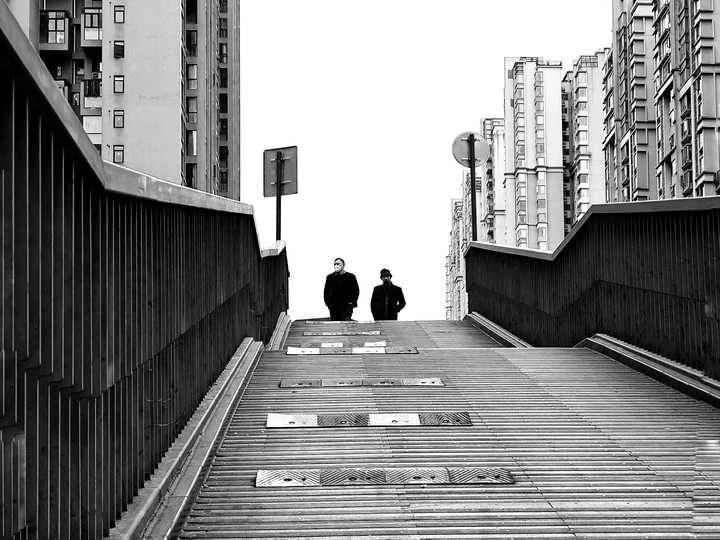 一个人在桥上走 背景是高大的建筑。