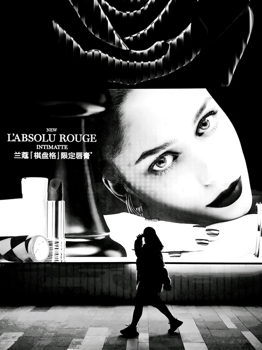 一张黑白电影海报 描绘了一位 woman 走在街道上 前方有一块大型广告牌。