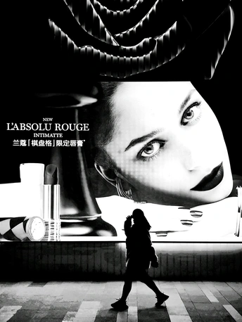 一张黑白电影海报 描绘了一位 woman 走在街道上 前方有一块大型广告牌。