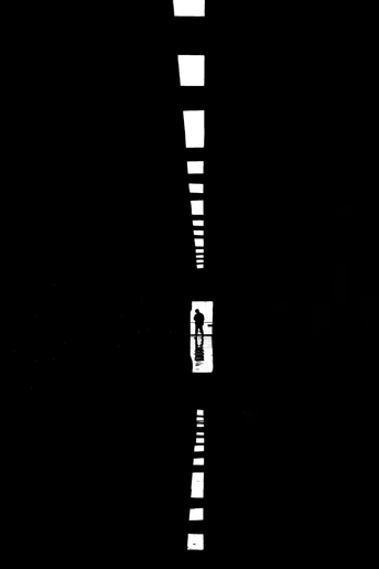 一条黑白相间的街道 中间有一条白色的线 一个人站在马路中间。