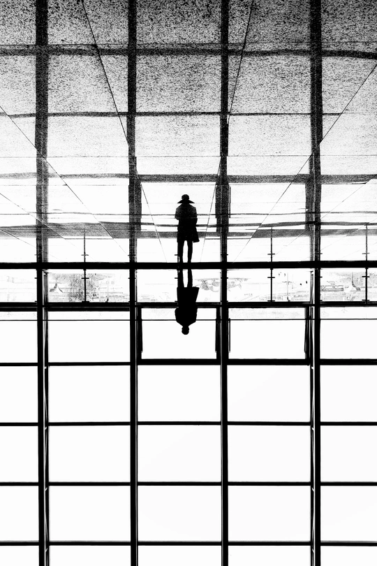 一个人和一个女人站在机场 注视着一座建筑物的窗户。