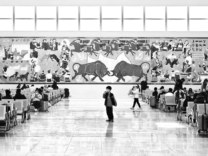 一张黑白照片 人们穿过机场 墙上有一幅大型壁画。