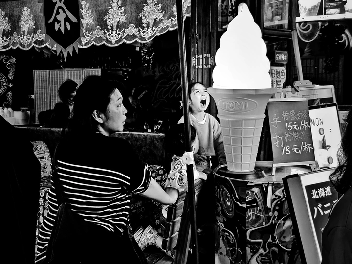 一位站在商店前的女人 手里拿着一杯东西。