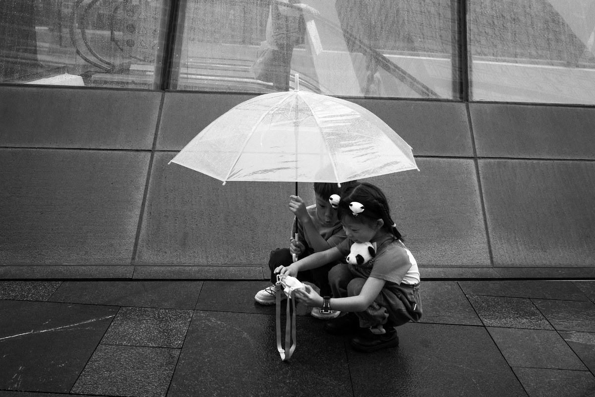 一个小女孩拿着雨伞坐在年轻人旁边