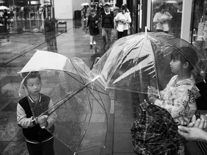 两个年轻男孩手持透明雨伞站在雨中