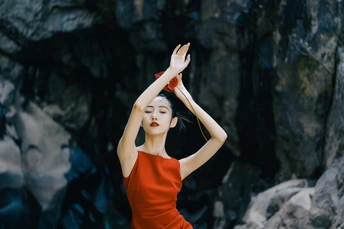 一个穿着橙色裙子的美丽女人站在她头上的洞穴岩石上