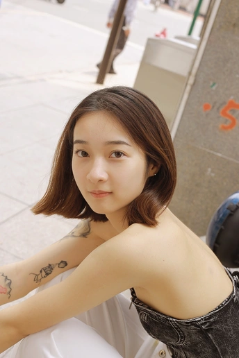 一个有纹身手臂的年轻女子与坐在背景中的人一起摆姿势