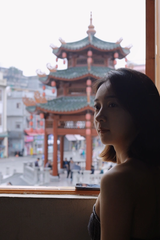 站在窗前向城市中的塔看去的一个年轻女子